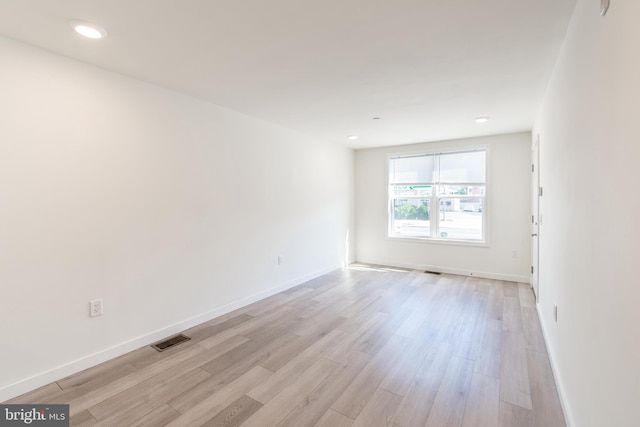 spare room featuring light wood-type flooring, visible vents, and baseboards