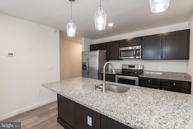 kitchen featuring a sink, stainless steel appliances, light wood-type flooring, baseboards, and dark brown cabinets