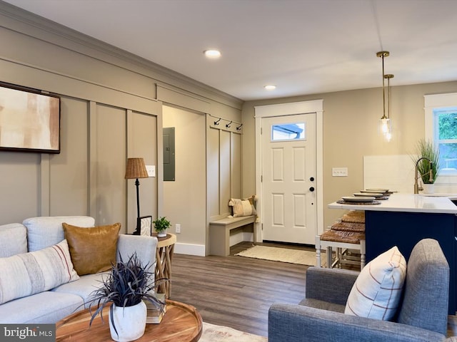 living room featuring electric panel, ornamental molding, and light hardwood / wood-style flooring