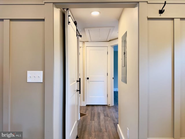 corridor with a barn door and dark hardwood / wood-style floors