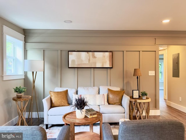 living room featuring ornamental molding, electric panel, and hardwood / wood-style flooring