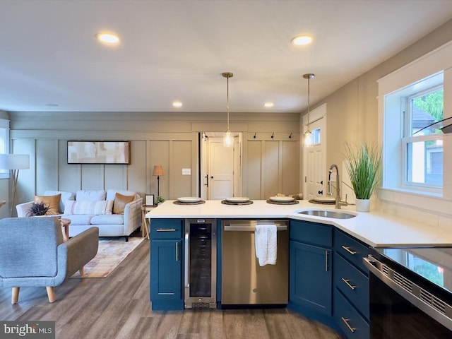 kitchen with sink, hanging light fixtures, stainless steel dishwasher, beverage cooler, and blue cabinetry