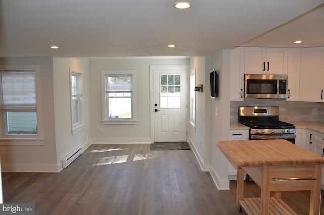 kitchen featuring appliances with stainless steel finishes, dark hardwood / wood-style flooring, tasteful backsplash, a baseboard radiator, and white cabinets