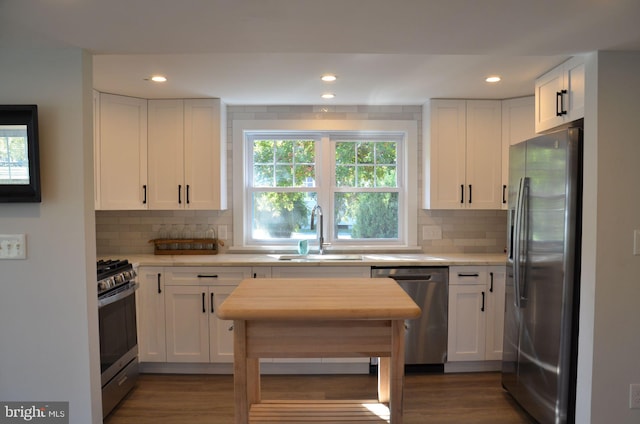 kitchen with white cabinets, appliances with stainless steel finishes, dark hardwood / wood-style floors, and sink