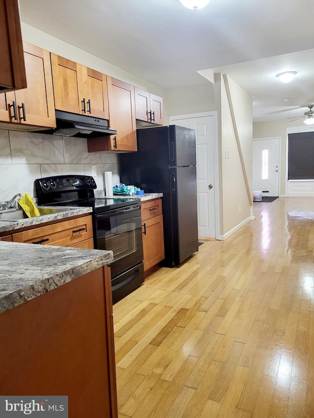 kitchen with ceiling fan, black appliances, light wood-type flooring, and decorative backsplash