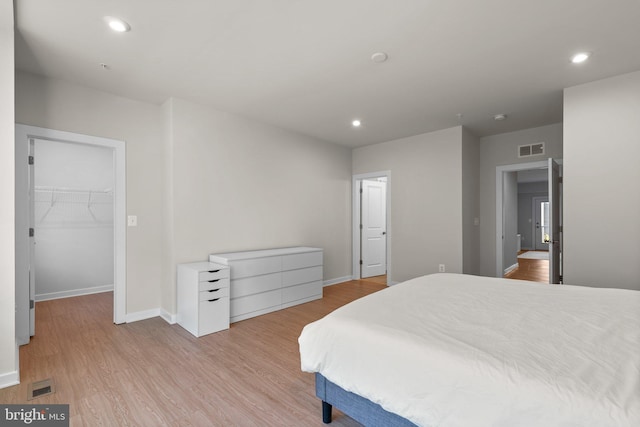 bedroom with a spacious closet, light wood-type flooring, and a closet