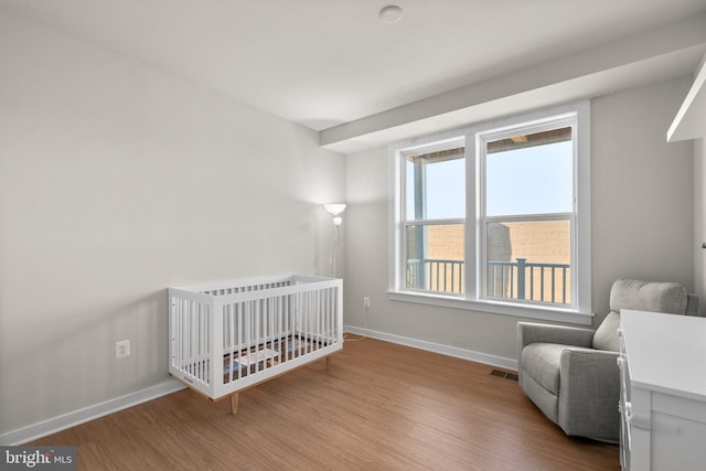 bedroom featuring light wood-type flooring and a nursery area