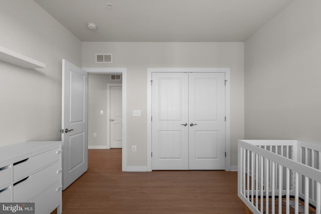 bedroom with a nursery area, light hardwood / wood-style flooring, and a closet