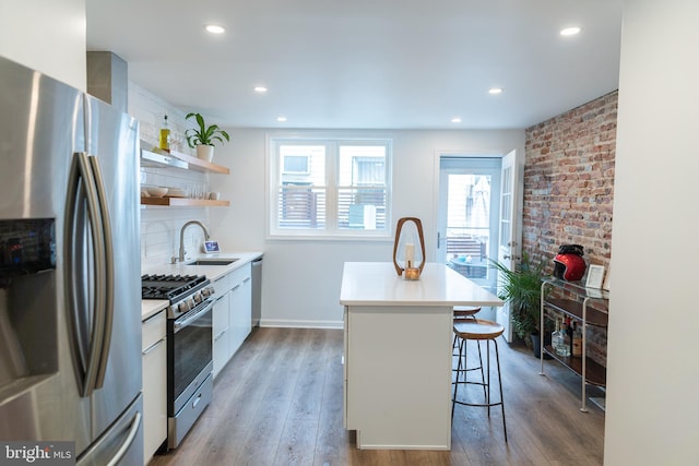 kitchen featuring sink, a kitchen island, a kitchen breakfast bar, hardwood / wood-style floors, and stainless steel appliances