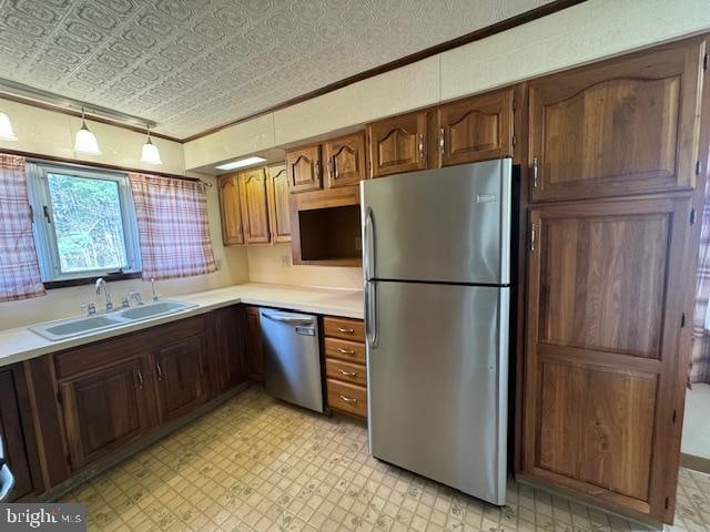 kitchen featuring stainless steel appliances, ornamental molding, sink, and a textured ceiling