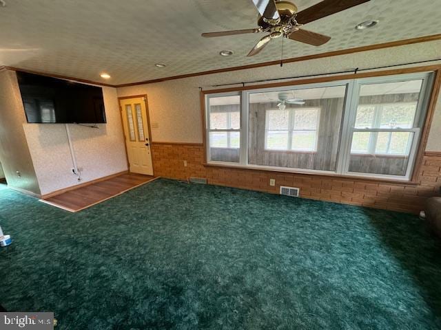 empty room featuring crown molding, wood-type flooring, a textured ceiling, and ceiling fan