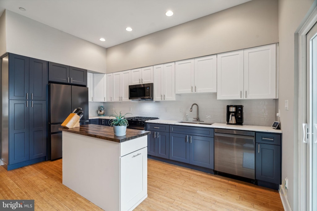 kitchen featuring white cabinetry, sink, a center island, stainless steel appliances, and wood counters