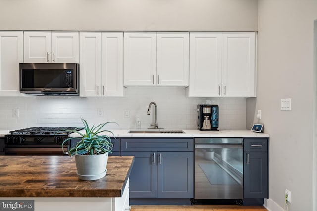 kitchen with sink, white cabinets, stainless steel appliances, and wood counters