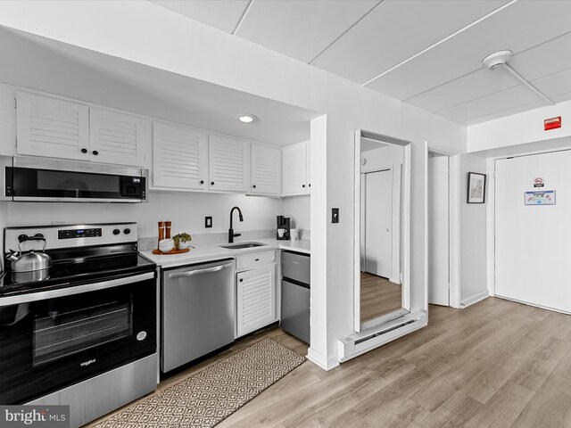 11204 Coastal Hwy Unit 9H, Ocean City, MD 21842 - kitchen featuring appliances with stainless steel finishes, a sink, light countertops, a baseboard heating unit, and white cabinetry