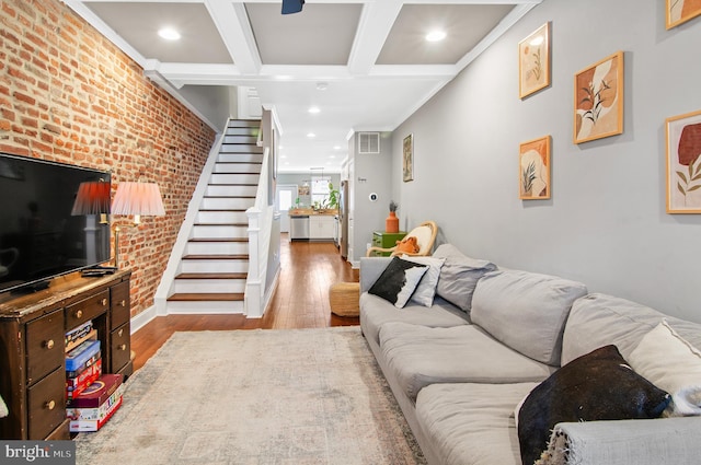 living room featuring beam ceiling, brick wall, and light hardwood / wood-style flooring