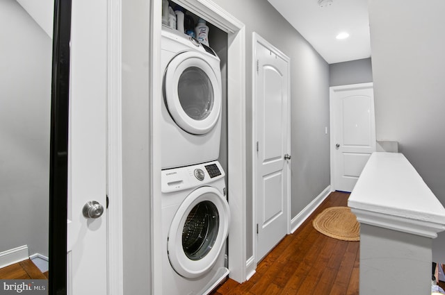 washroom with dark wood-type flooring and stacked washer / dryer