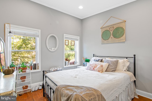 bedroom with multiple windows, wood-type flooring, and crown molding