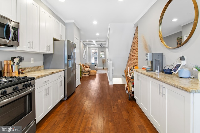 kitchen featuring dark hardwood / wood-style floors, ornamental molding, white cabinetry, appliances with stainless steel finishes, and light stone counters