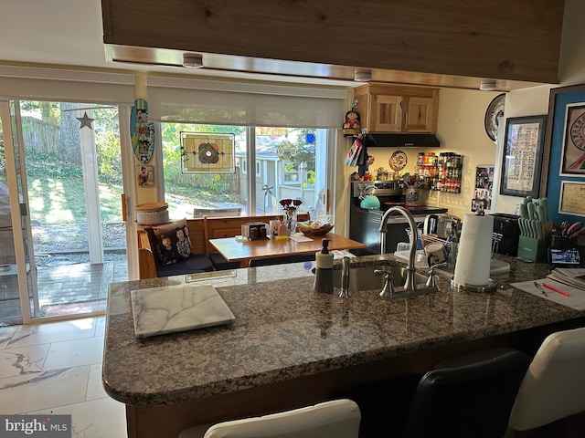 kitchen featuring kitchen peninsula, stone counters, sink, and stainless steel range with electric cooktop