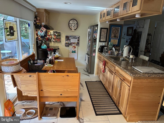 kitchen featuring stainless steel refrigerator, dark stone counters, and sink