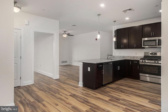 kitchen with kitchen peninsula, hanging light fixtures, ceiling fan, stainless steel appliances, and hardwood / wood-style flooring