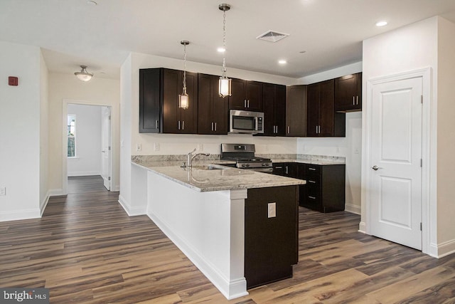 kitchen featuring dark brown cabinetry, appliances with stainless steel finishes, kitchen peninsula, and dark hardwood / wood-style floors