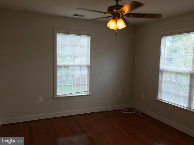 spare room with dark wood-type flooring and ceiling fan