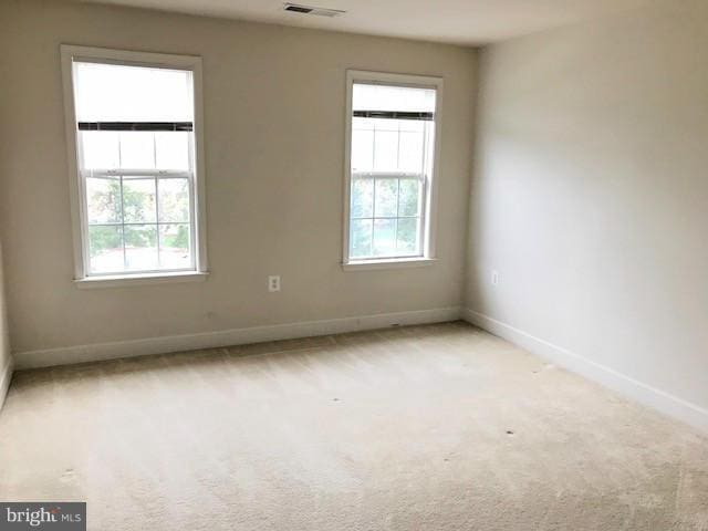 spare room featuring a healthy amount of sunlight and light colored carpet