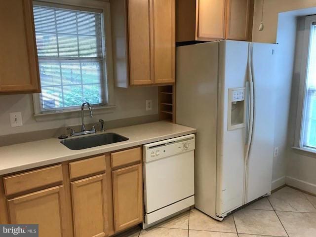 kitchen featuring light brown cabinetry, sink, white appliances, and light tile patterned floors