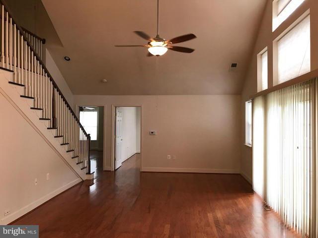 unfurnished living room with high vaulted ceiling, dark wood-type flooring, plenty of natural light, and ceiling fan