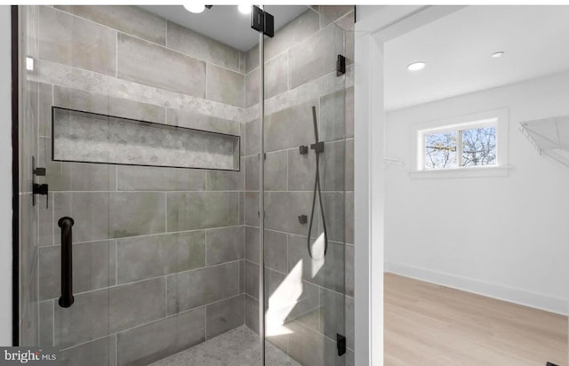 bathroom with a shower with door and wood-type flooring