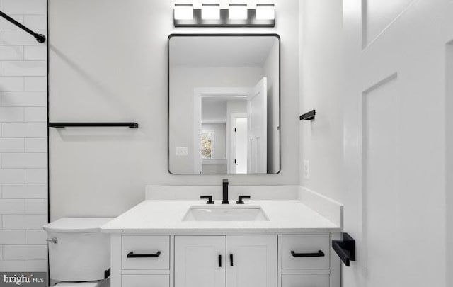 bathroom featuring vanity, toilet, and a tile shower