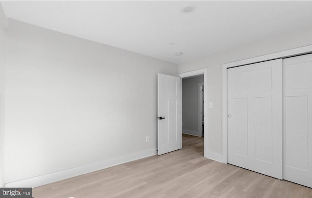 unfurnished bedroom with a closet and light hardwood / wood-style floors