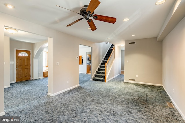 unfurnished living room featuring dark colored carpet and ceiling fan