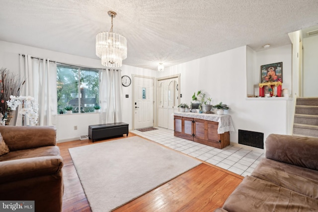 living room with an inviting chandelier, a textured ceiling, and light wood-type flooring