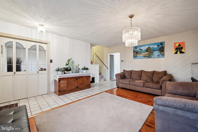 living room featuring a textured ceiling, a notable chandelier, and light hardwood / wood-style floors