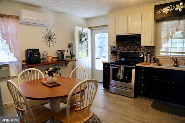 kitchen featuring a wall mounted AC, extractor fan, sink, stainless steel electric range, and light hardwood / wood-style floors