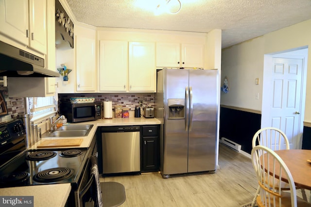 kitchen with a baseboard heating unit, appliances with stainless steel finishes, a textured ceiling, light hardwood / wood-style floors, and sink