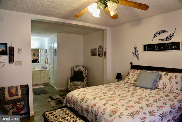 bedroom with dark wood-type flooring, ceiling fan, a textured ceiling, and ensuite bath