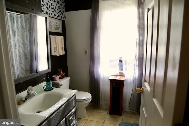 bathroom featuring a healthy amount of sunlight, vanity, toilet, and tile patterned floors