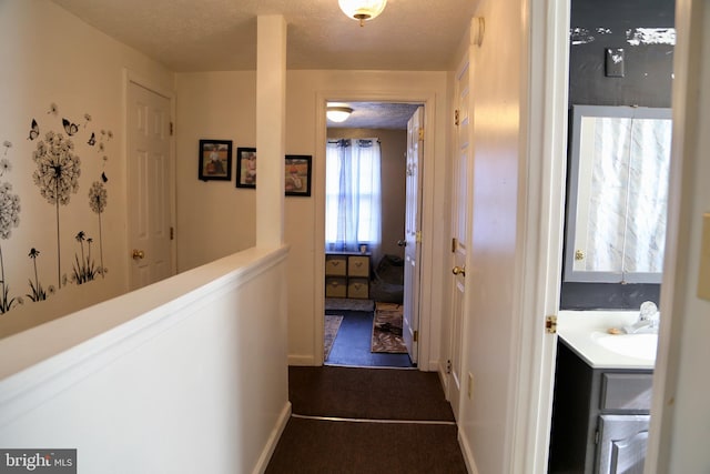 hall featuring a textured ceiling and sink