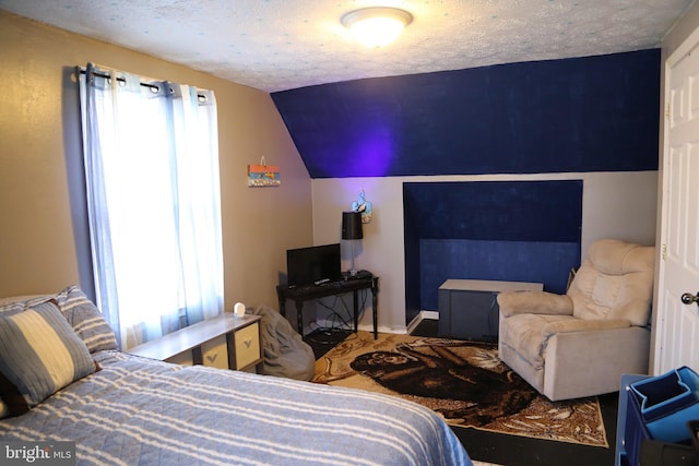 bedroom featuring a textured ceiling, vaulted ceiling, and multiple windows