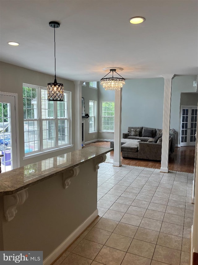 kitchen with ornate columns, decorative light fixtures, a wealth of natural light, and light tile patterned floors