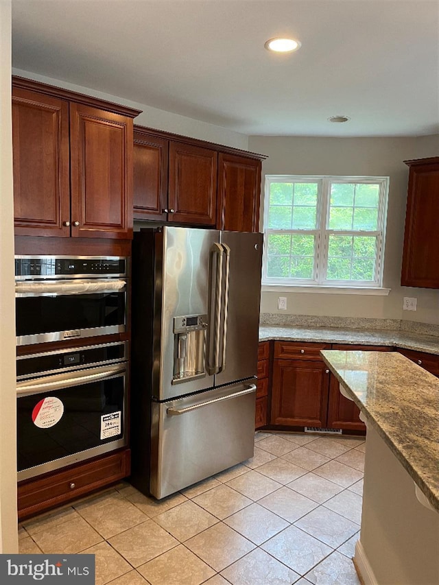 kitchen with appliances with stainless steel finishes, light stone countertops, and light tile patterned flooring