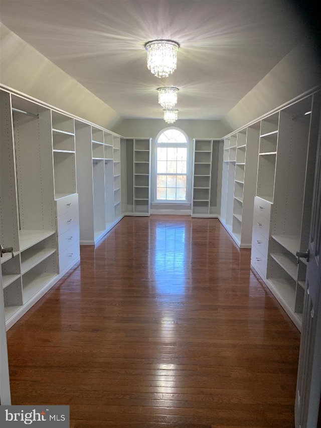 spacious closet with dark wood-type flooring and a notable chandelier