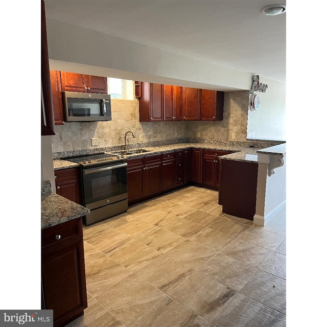 kitchen featuring stone countertops, stainless steel appliances, tasteful backsplash, and sink