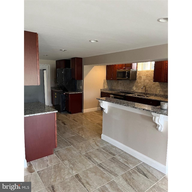 kitchen with dark stone countertops, tasteful backsplash, and stove