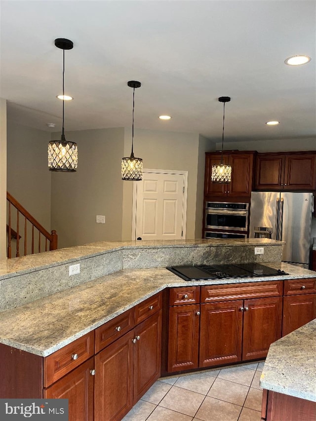 kitchen featuring light stone countertops, light tile patterned flooring, appliances with stainless steel finishes, and decorative light fixtures