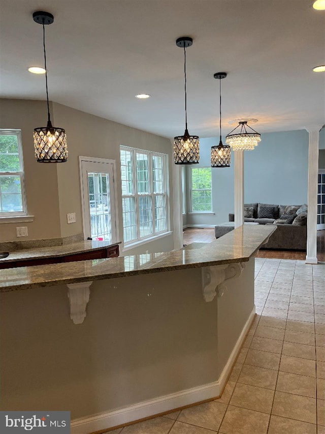 kitchen featuring light stone counters, pendant lighting, ornate columns, and light tile patterned floors