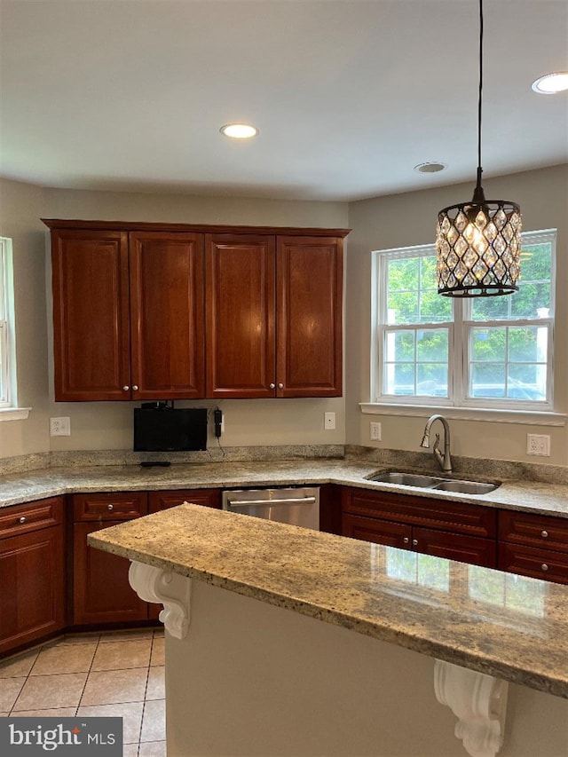 kitchen with hanging light fixtures, sink, light tile patterned flooring, stainless steel dishwasher, and light stone counters